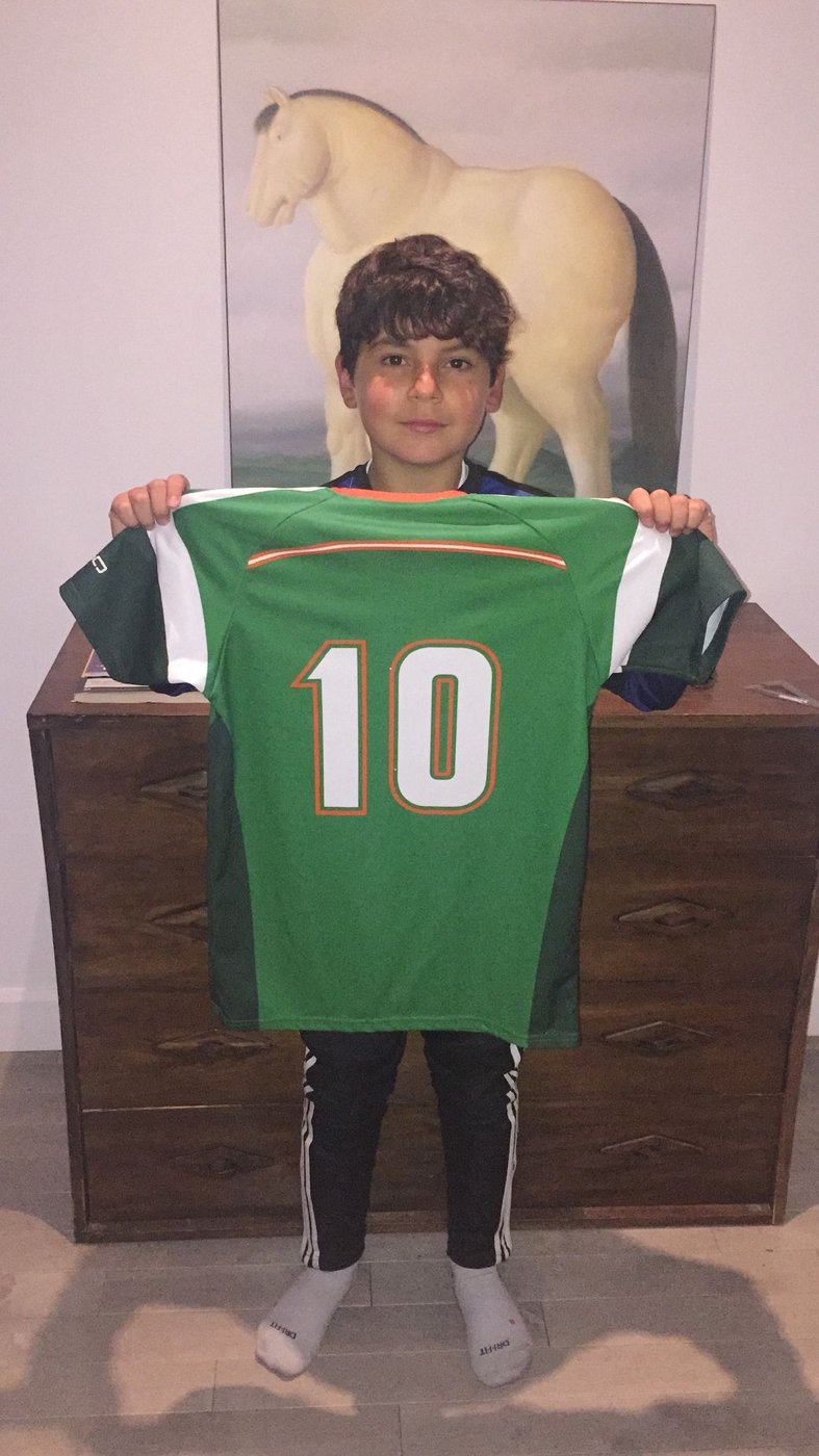 Nico holding up the green number 10 Caravelles shirt